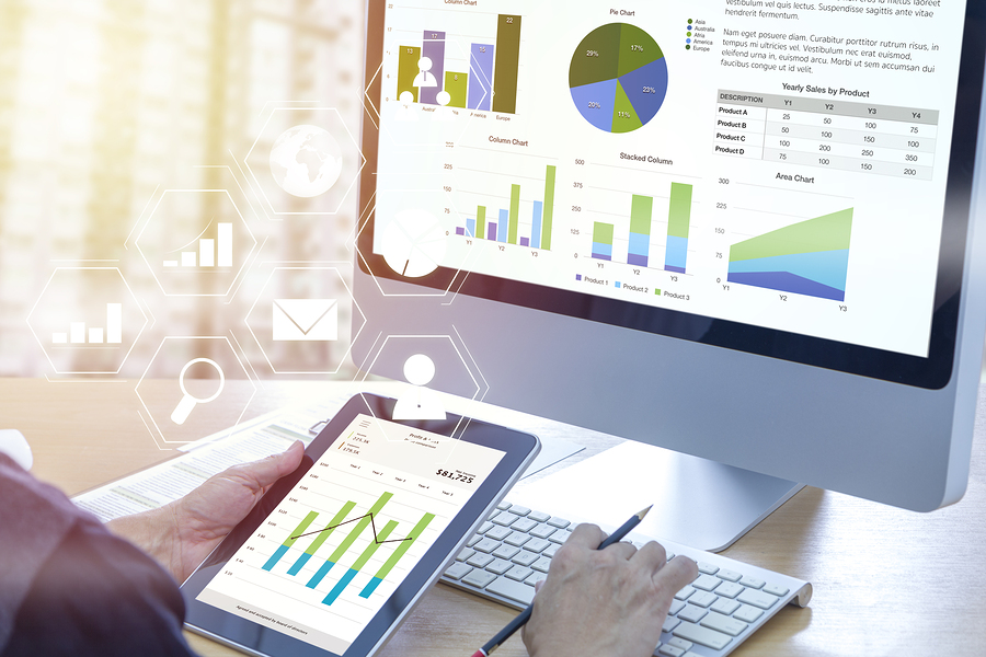 Businessman in front of modern computer with colorful pie and bar graphs analyzing business performance accounting data. Displaying full-charge bookkeeping service